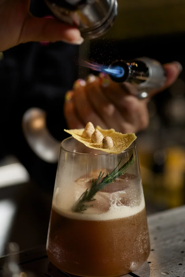 Cóctel de autor durante su terminación con una llama en la barra de Banús.
